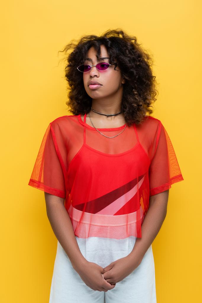 göndör afro-amerikai nő divatos napszemüveg és nyári ruha elszigetelt sárga - Fotó, kép