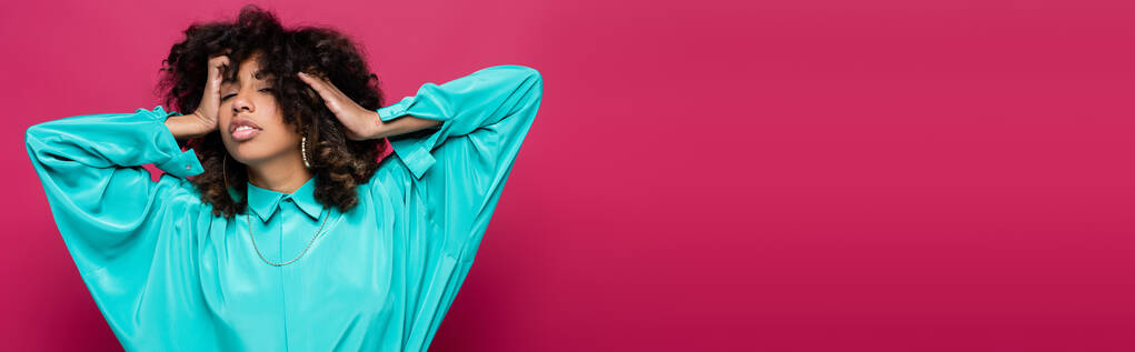 sensual mujer afroamericana con los ojos cerrados tocando pelo aislado en rosa, pancarta - Foto, imagen