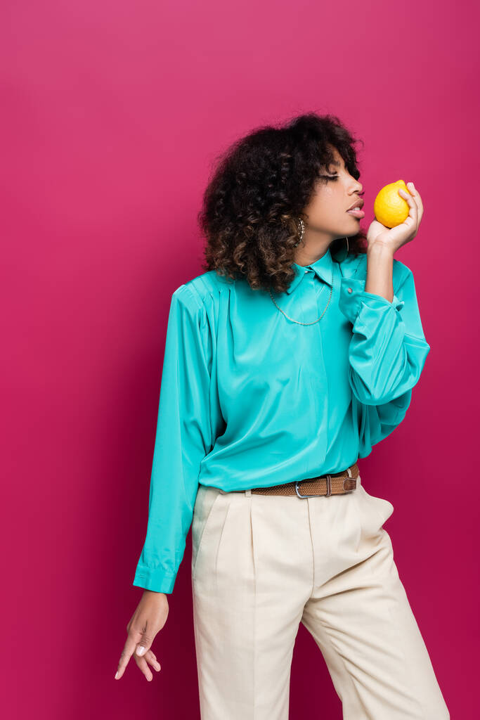 Cyan bluzlu Afro-Amerikan kadın pembe üzerinde aromatik limon tutuyor. - Fotoğraf, Görsel