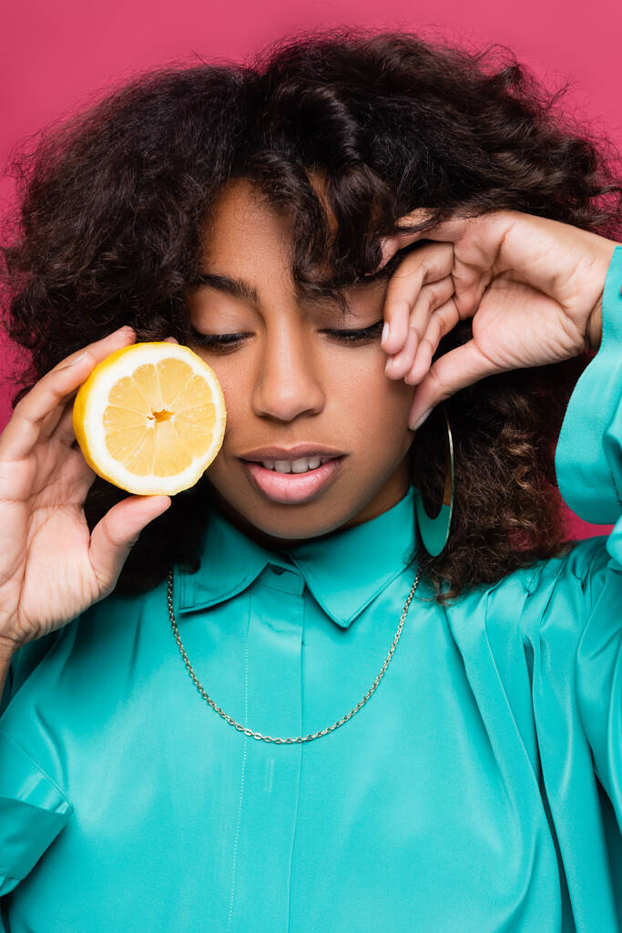 стильная африканская американская женщина со свежим лимоном и рукой рядом лицо изолировано на розовый - Фото, изображение