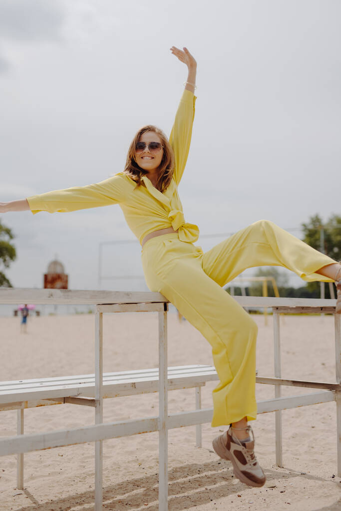 Boldog fiatal nő sárga ruhában a parton - Fotó, kép
