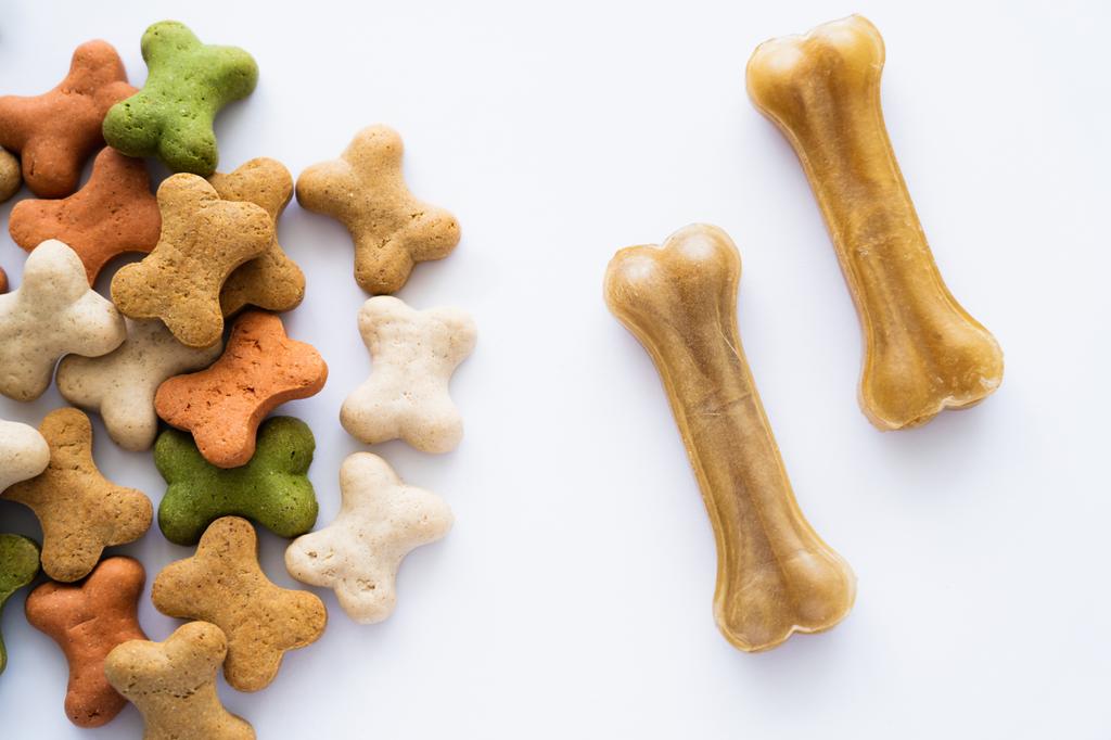 Ansicht von knusprigen, knochenförmigen Keksen und Leckereien für Hund isoliert auf weiß - Foto, Bild