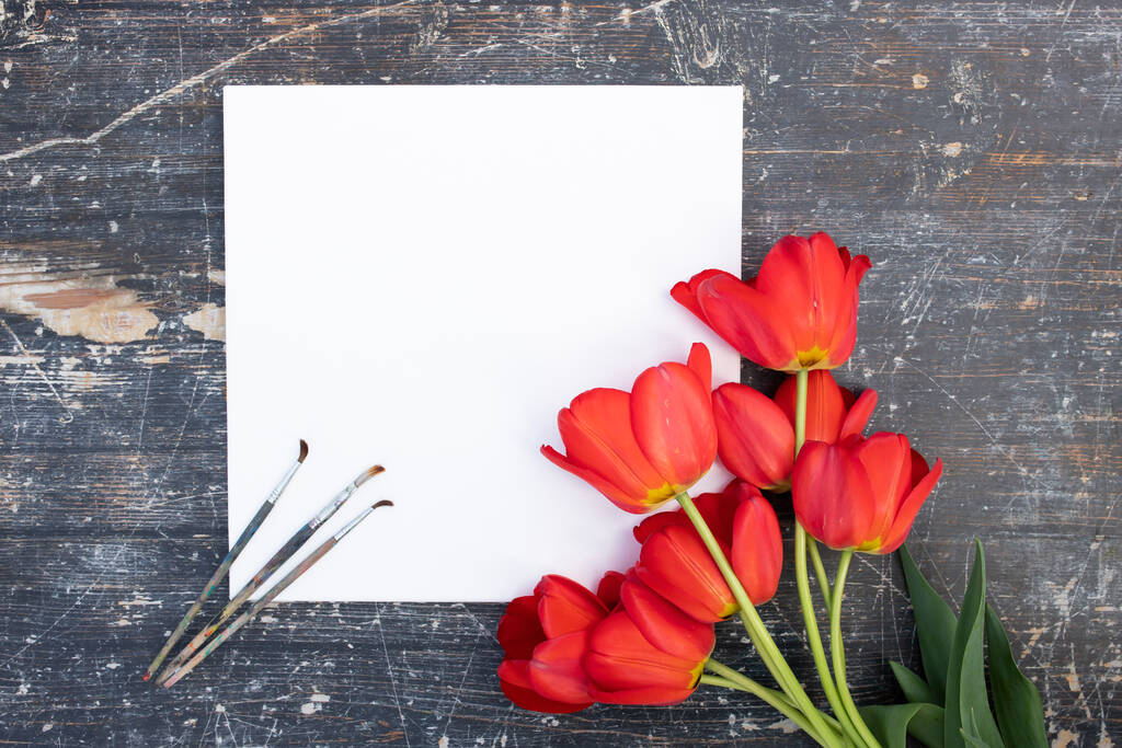 Concepto creativo de primavera hecho con pincel de pintura y flores de tulipán rojo sobre fondo de madera. - Foto, imagen