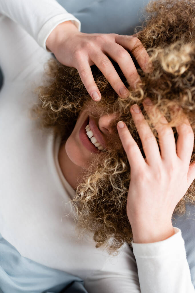 ylhäältä näkymä hymyilevä nainen peittää kasvot kihara tukka - Valokuva, kuva