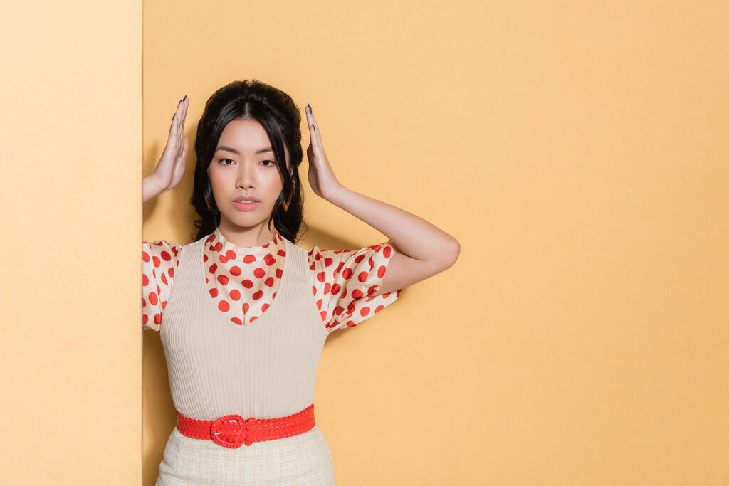 Modèle asiatique en vêtements vintage posant sur fond orange - Photo, image