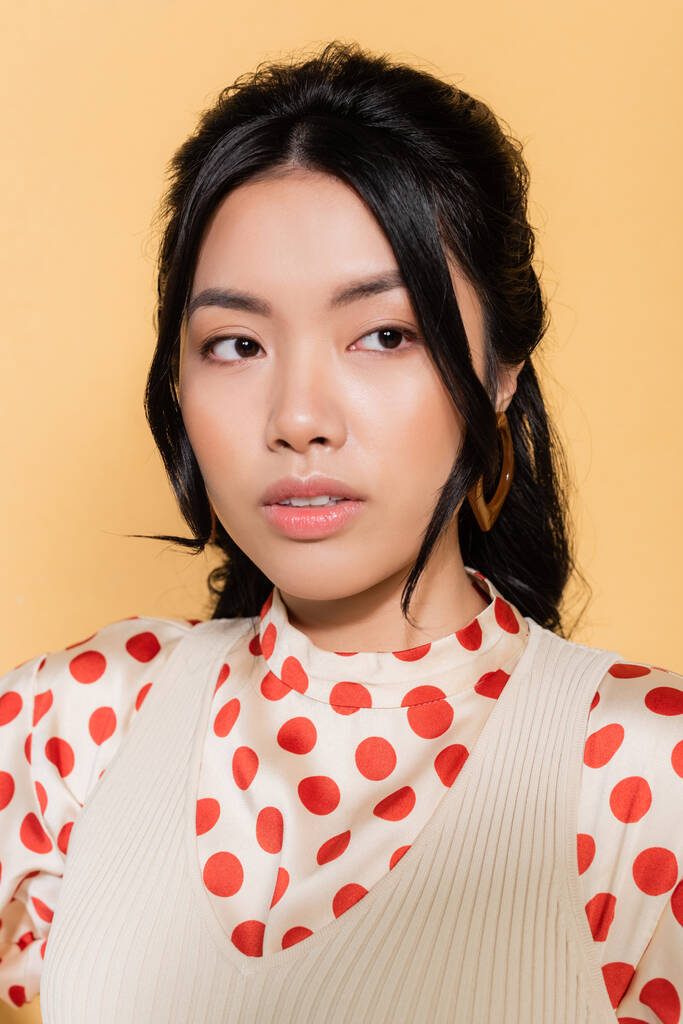 Portrét stylové asijské ženy dívá pryč izolované na oranžové  - Fotografie, Obrázek