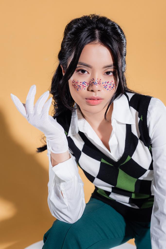 Stylish asian model with makeup posing on orange background - Photo, Image