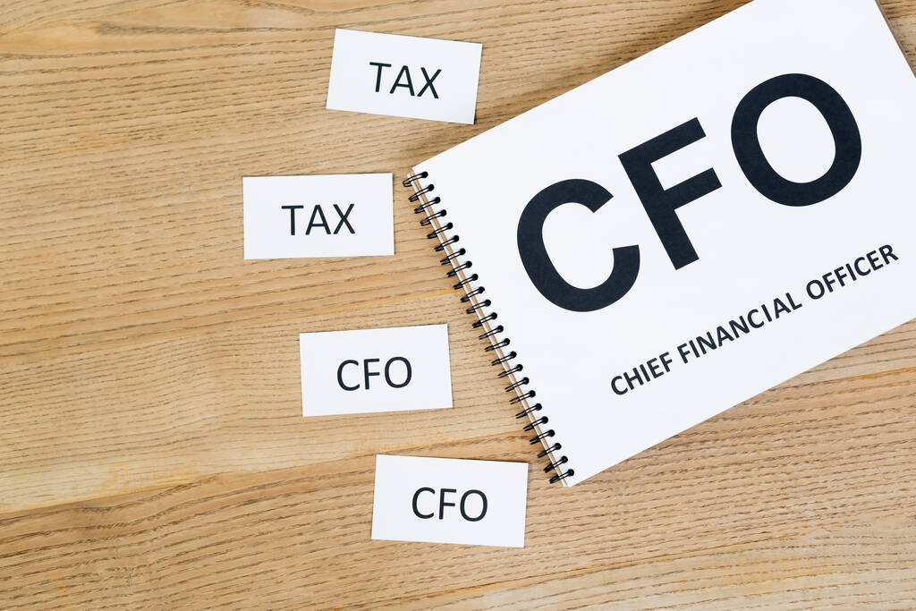 felső nézet a notebook cfo és a vezető pénzügyi tisztviselő betű közelében papírok rövidítés az asztalon - Fotó, kép