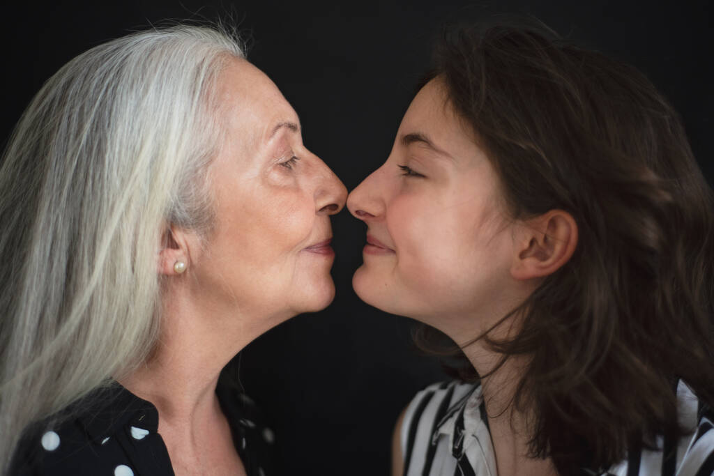 Büyük büyükannesiyle torununun siyah kara zeminde yüz yüze duran bir portresi. - Fotoğraf, Görsel