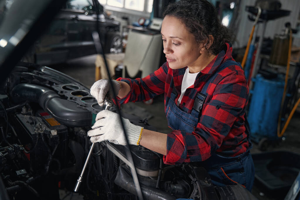 Ženský technik vozidla pomocí kovového momentového klíče při opravě automobilového motoru v autoopravně - Fotografie, Obrázek