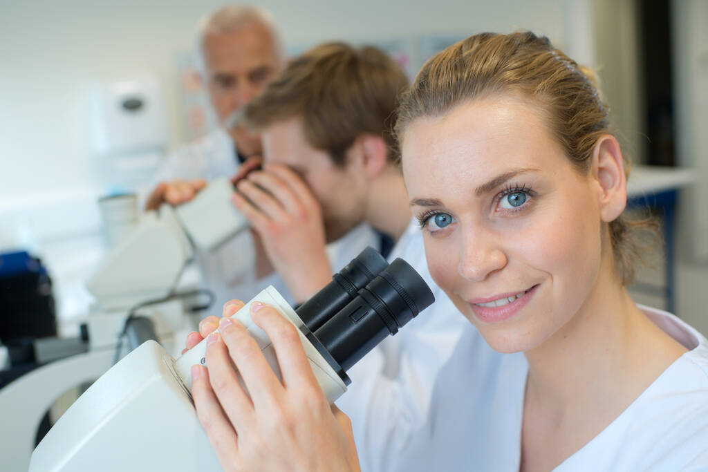 médico bonita fêmea usando um microscópio - Foto, Imagem