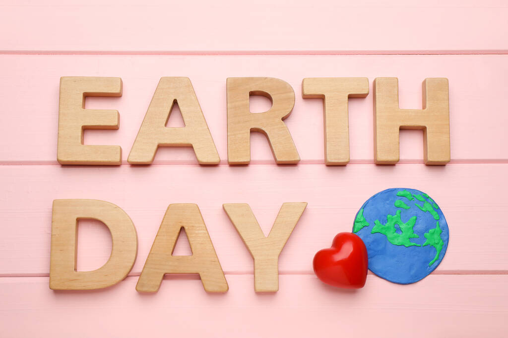 Λέξεις Ημέρα της Γης, πλαστικός πλανήτης και διακοσμητική καρδιά σε ροζ ξύλινο τραπέζι, επίπεδη lay - Φωτογραφία, εικόνα