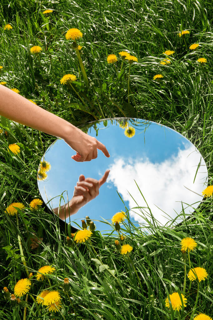 concetto di natura - mano toccante riflesso del cielo in specchio rotondo sul campo estivo - Foto, immagini