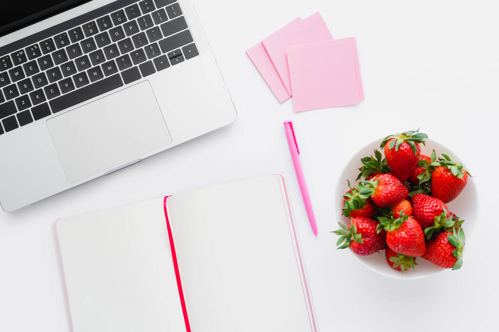 Top näkymä kannettavan tietokoneen lähellä kannettavan ja maukkaita mansikoita valkoisella pohjalla - Valokuva, kuva