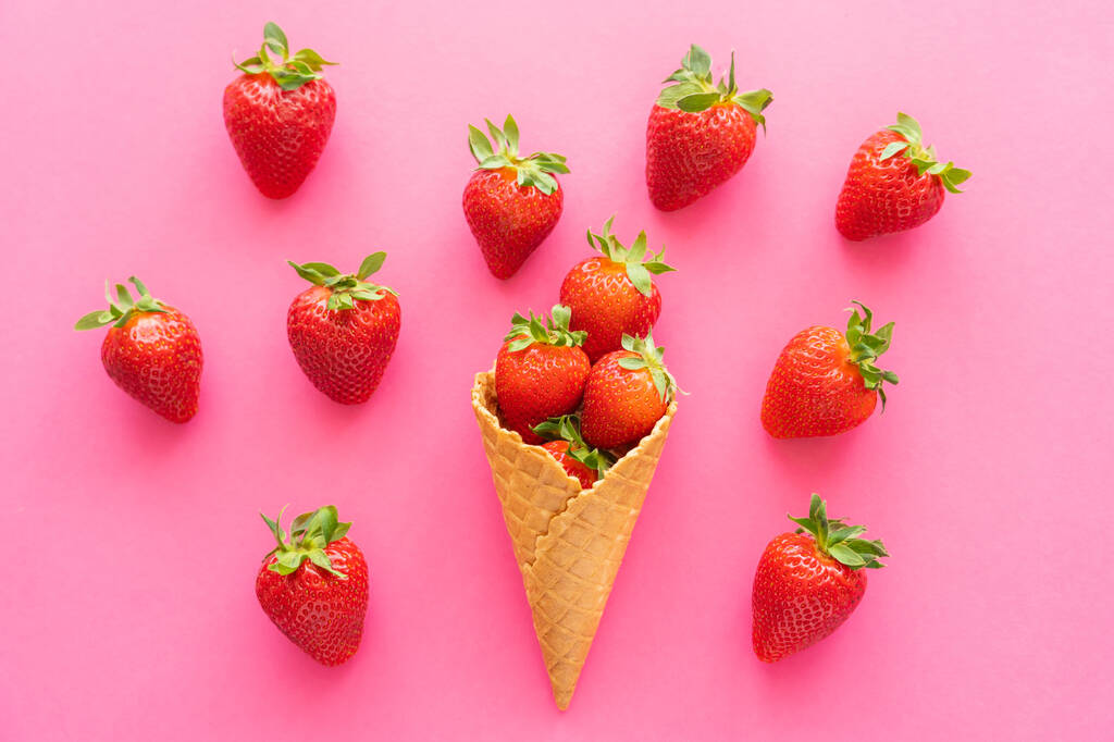 Draufsicht auf reife Erdbeeren und Waffelkegel auf rosa Hintergrund  - Foto, Bild
