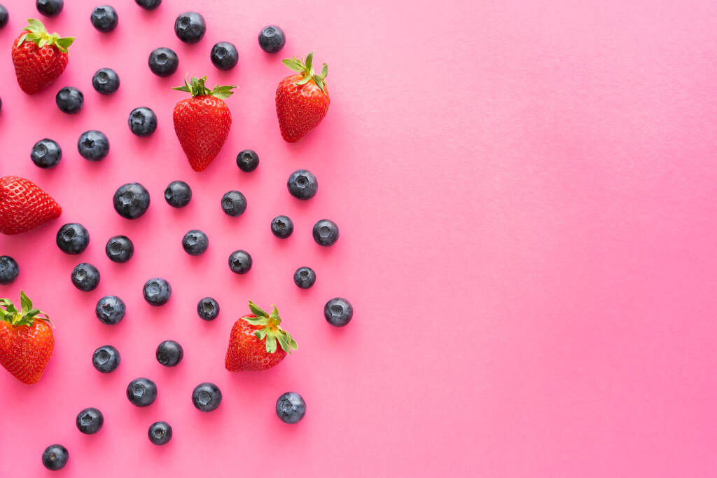 Flache Lage mit Blaubeeren und Erdbeeren auf rosa Oberfläche - Foto, Bild
