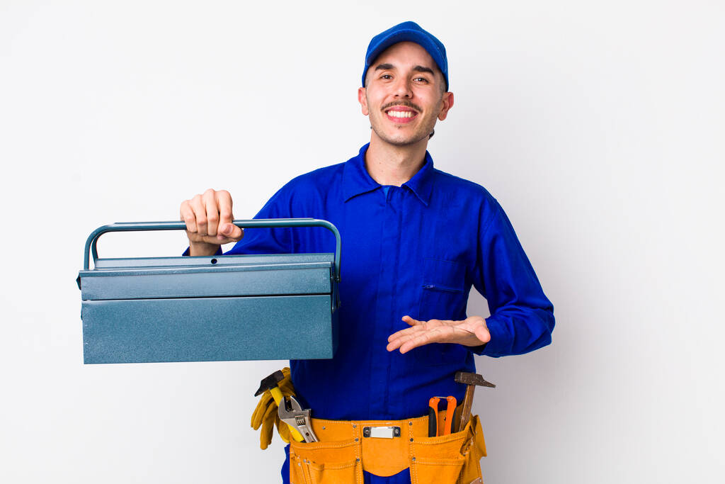 jonge Spaanse loodgieter glimlacht vrolijk, voelt zich gelukkig en toont een concept. toolbox concept - Foto, afbeelding