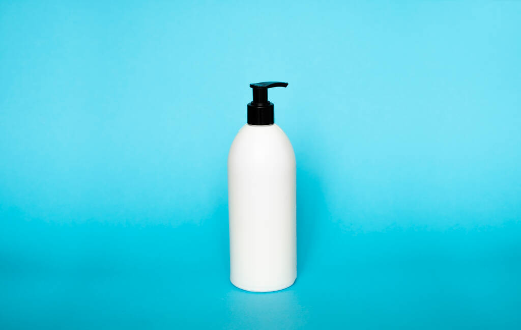 Valkoinen muovipullo shampoo, hoitoaine tai suihkugeeli sinisellä pohjalla. Mallintaa mallin suunnittelu - Valokuva, kuva
