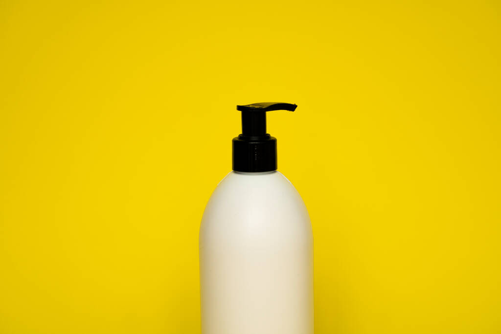 Recipiente líquido para gel, loción, crema, champú, espuma de baño sobre fondo amarillo. Botella de plástico cosmético con bomba dispensadora blanca. Plantilla simulada para el diseño - Foto, Imagen
