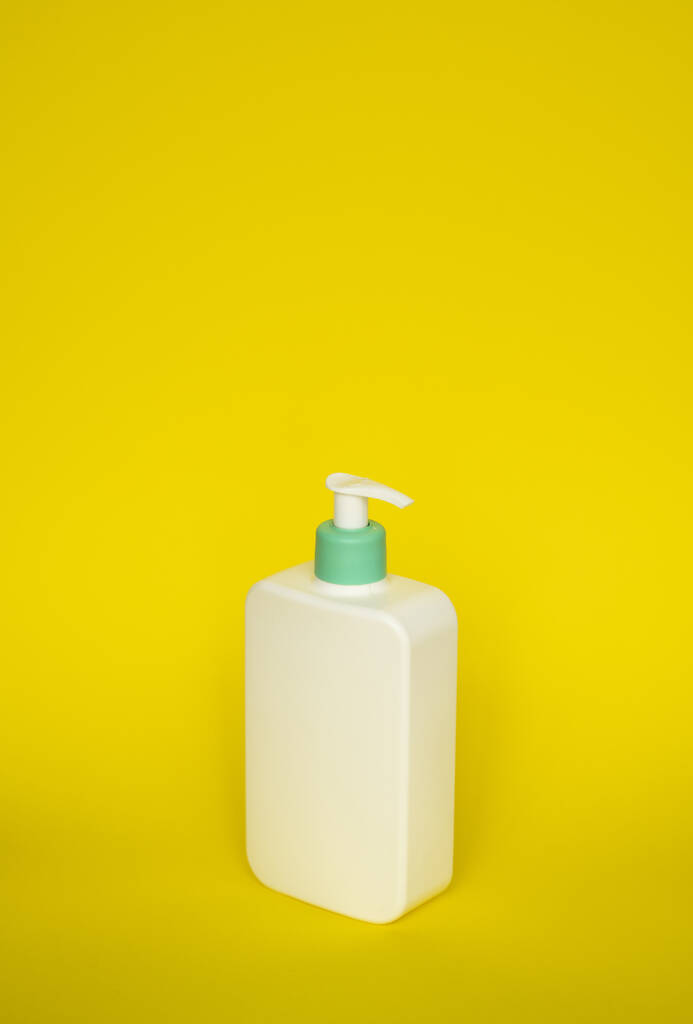 Sarı arka planda şeker pompalı şampuan ya da saç kremi şişesi. - Fotoğraf, Görsel