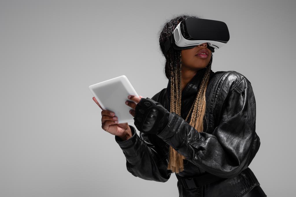 アフリカ系アメリカ人女性のvrヘッドセット保持デジタルタブレットゲームはグレーに隔離されながら  - 写真・画像