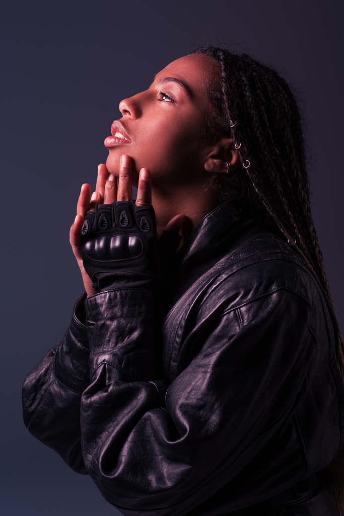 Deri ceketli ve eldivenli Afro-Amerikan kadının koyu gri renkte izole edilmiş bakışları.  - Fotoğraf, Görsel