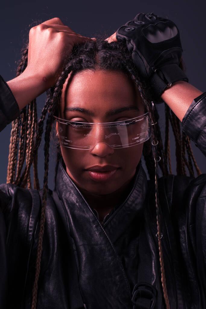 Retrato de mujer afroamericana con estilo usando gafas inteligentes aisladas en gris oscuro  - Foto, imagen