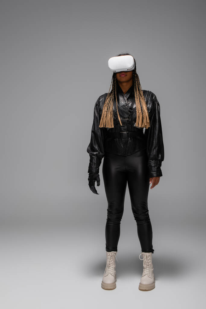 African american woman in cyber glove and vr headset on grey background - Photo, Image