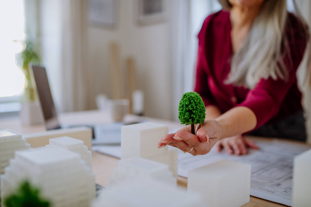 Eine Nahaufnahme hochrangiger Öko-Architektinnen mit Modell moderner Gebäude und Entwürfe, die im Büro zusammenarbeiten. - Foto, Bild
