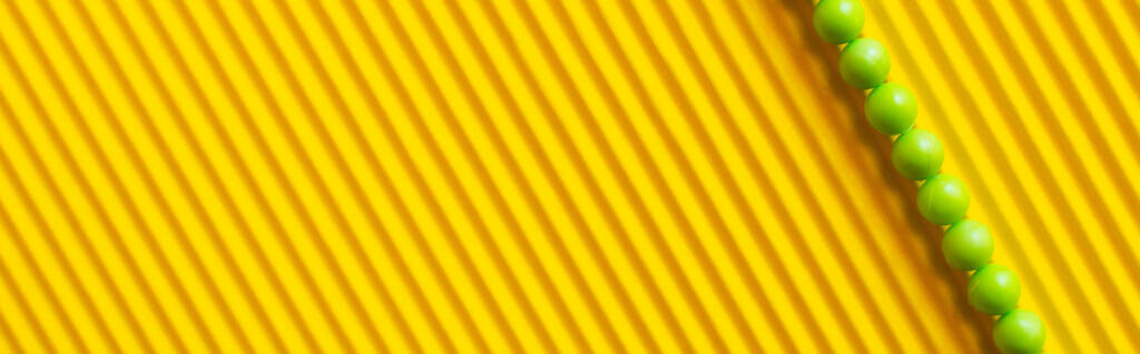 top view of small green balls on striped yellow background with copy space, banner - Photo, Image