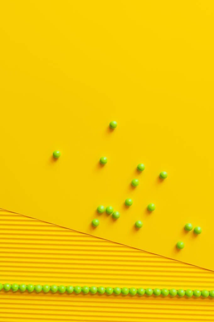 ylhäältä näkymä vihreitä helmiä hajallaan keltainen kuvioitu tausta - Valokuva, kuva