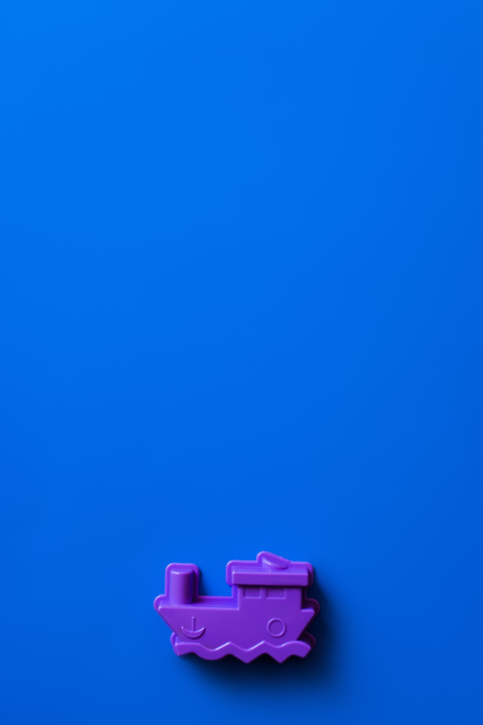 horní pohled na fialové hračky loď na modrém pozadí s kopírovacím prostorem - Fotografie, Obrázek
