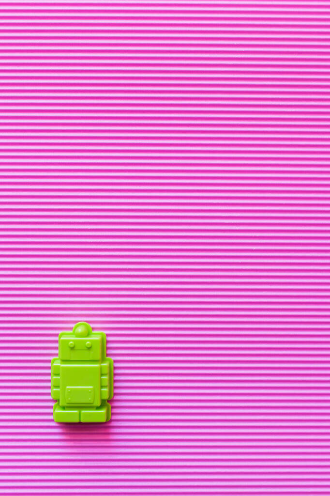 vista superior del molde verde brillante en forma de robot sobre fondo violeta texturizado - Foto, Imagen