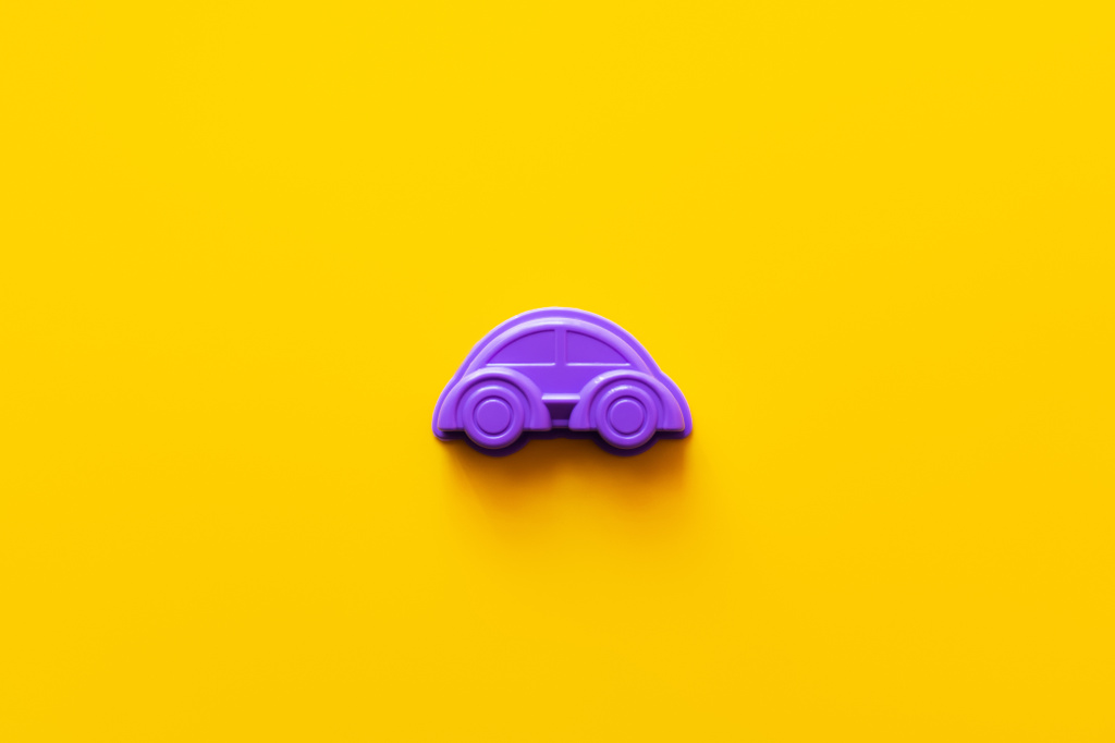 鮮やかな黄色の背景に紫色のプラスチック製の車のトップビュー - 写真・画像