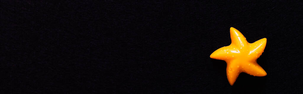 πάνω όψη του ανοιχτού κίτρινου πλαστικού αστερία που απομονώνεται σε μαύρο, banner - Φωτογραφία, εικόνα