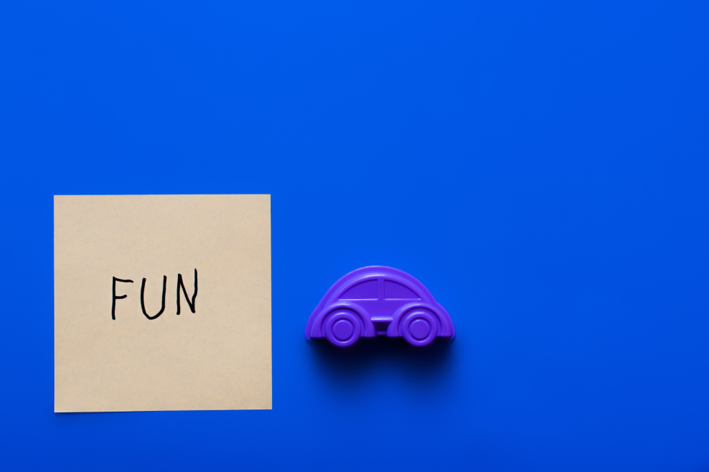 vista superior de papel con letras divertidas cerca del molde de coche púrpura sobre fondo azul - Foto, Imagen