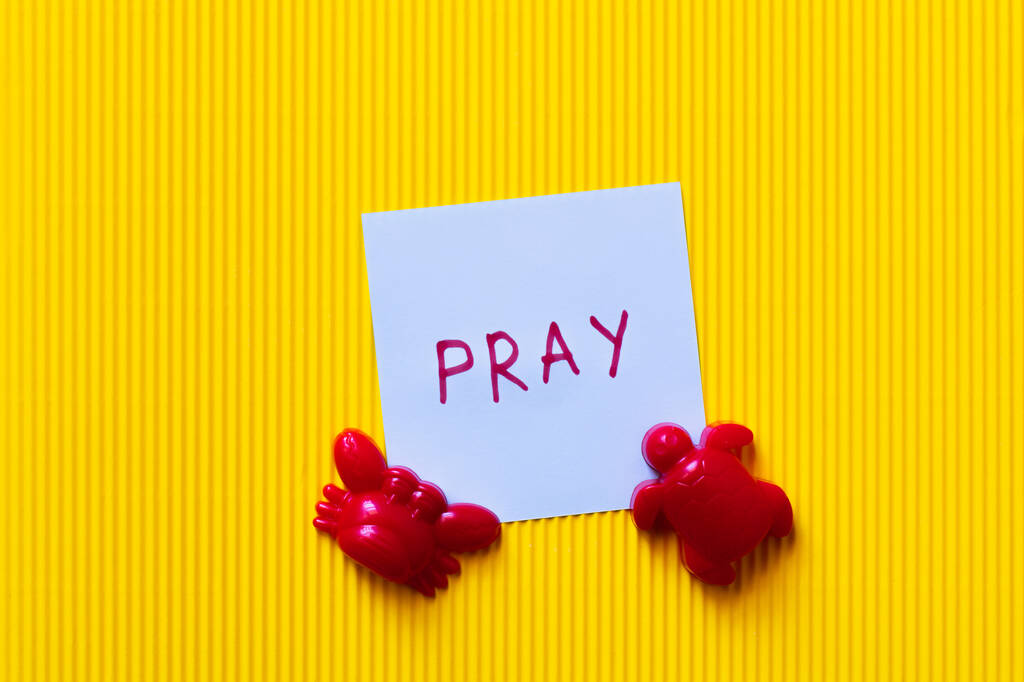 黄色の背景にカニや亀のおもちゃの近くに祈りのレタリングを持つカードのトップビュー - 写真・画像