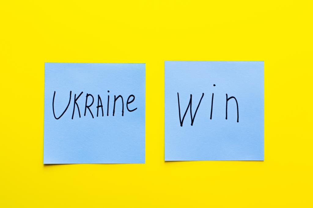vue du dessus des papiers bleus avec lettrage ukraine win sur fond jaune - Photo, image