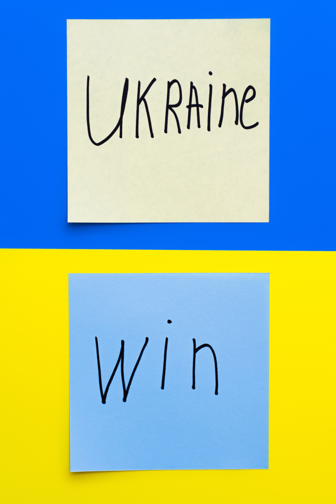 top view of papers with ukraine win lettering on blue and yellow background - Photo, Image