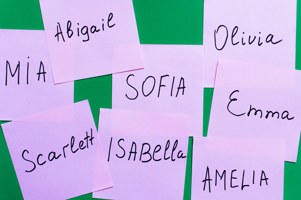 widok z góry blado fioletowe karty z imionami kobiet na zielonym tle - Zdjęcie, obraz