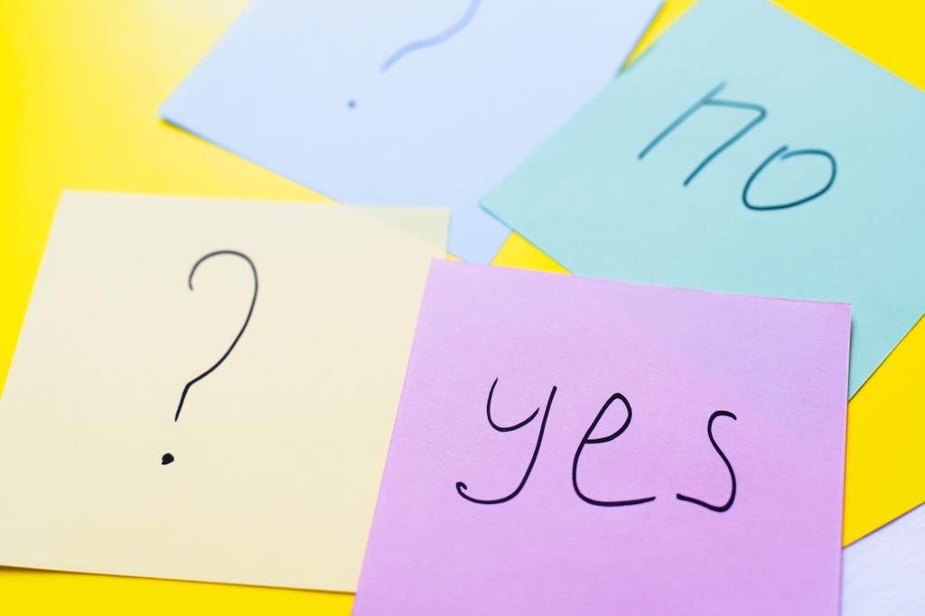 mehrfarbige Papiere mit Ja und Nein in der Nähe von Fragezeichen auf gelbem Hintergrund - Foto, Bild