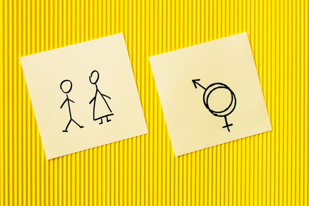 黄色のテクスチャの背景にオスとメスのアイコンと性別記号を持つカードの上からの眺め - 写真・画像