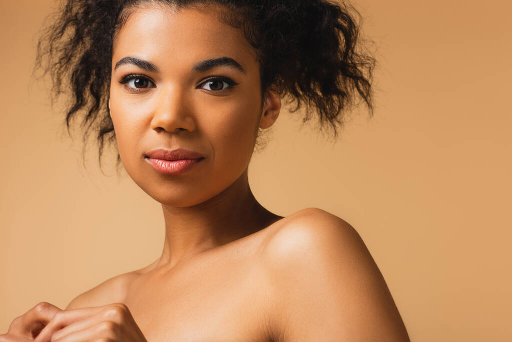 bella giovane donna africana americana con le spalle nude isolate sul beige  - Foto, immagini