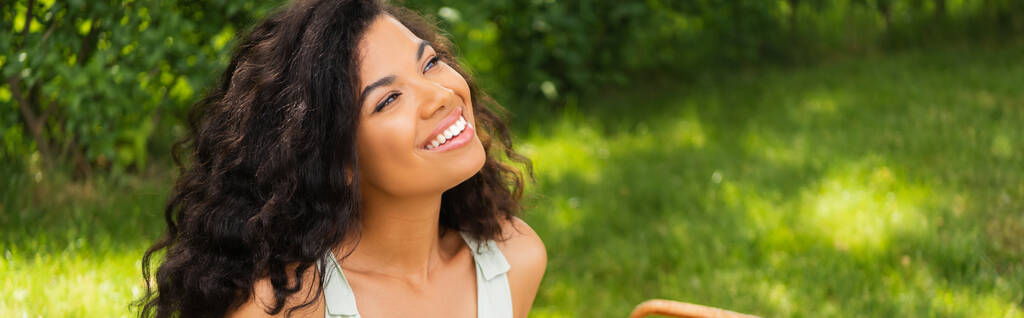 мрійлива афроамериканка посміхається і дивиться в зелений парк, банер
 - Фото, зображення