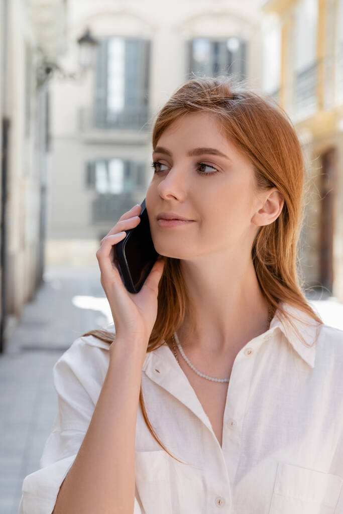 портрет рудої жінки, що розмовляє на смартфоні і дивиться у валенсію
 - Фото, зображення