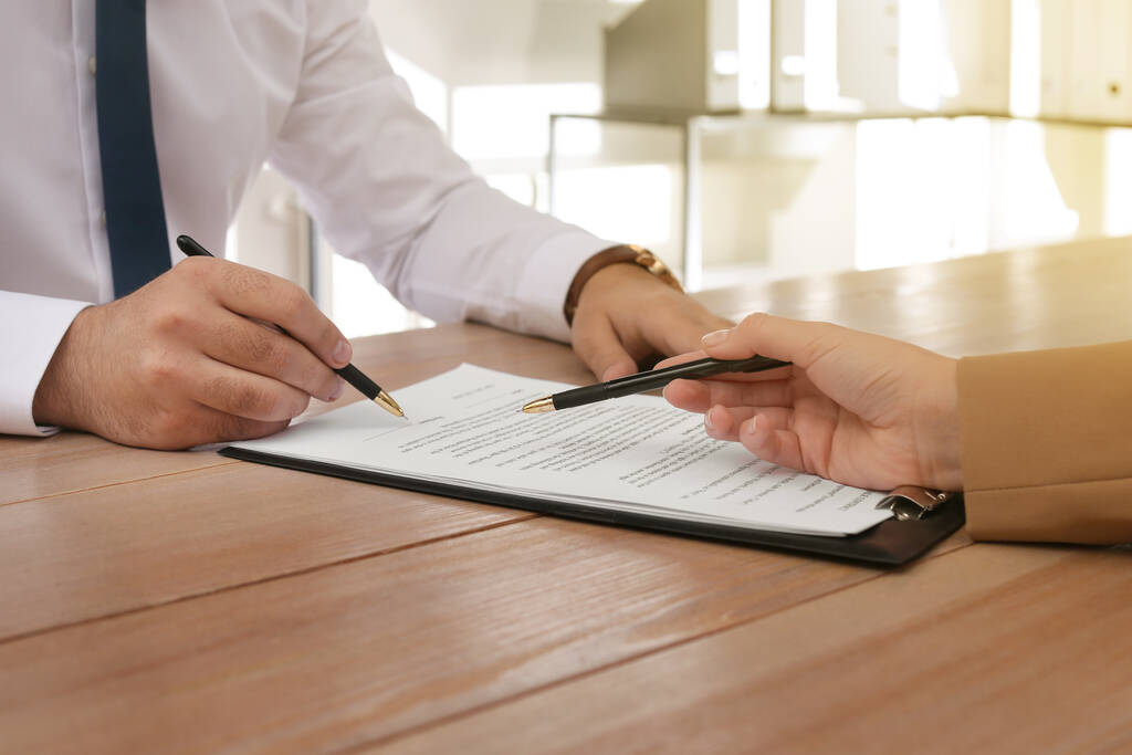 Человек подписывает документы за деревянным столом в офисе, крупным планом. Концепция страхования - Фото, изображение