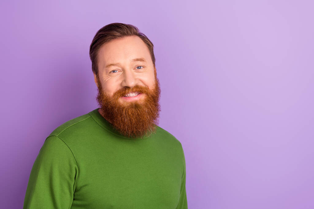 Fénykép a jó hangulat jóképű vörhenyes férfi mosolyog a kamera kopás zöld pulóver elszigetelt lila színű háttér. - Fotó, kép