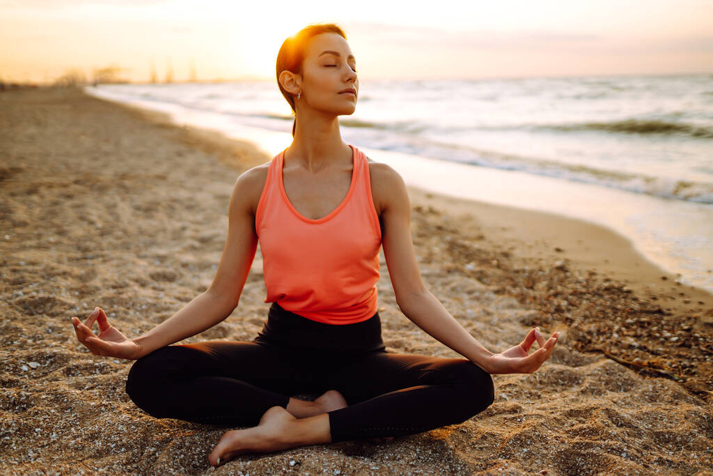 Genç ve güzel bir kadın yoga yapıyor ve sahilde meditasyon yapıyor. Spor, Aktif Yaşam.  - Fotoğraf, Görsel