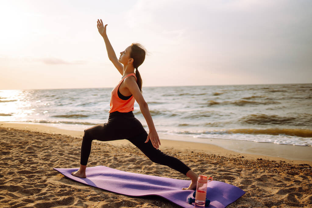 Fiatal nő a sportruházatban jógázik, fitneszgyakorlatozik a strandon. Sport, aktív élet.  - Fotó, kép