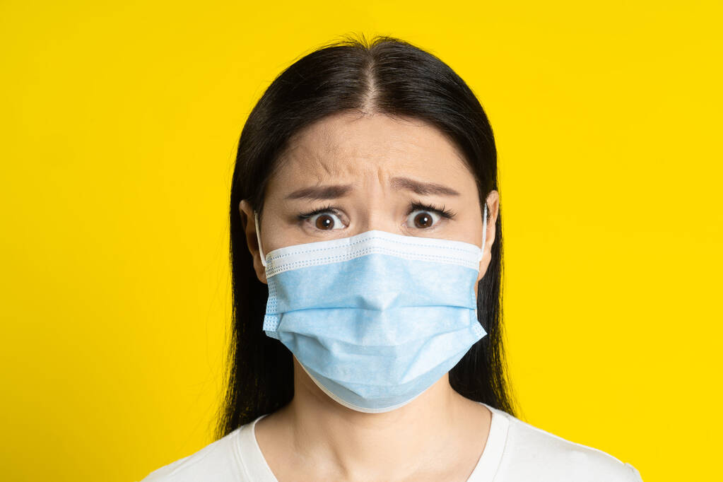 Tıbbi yüz maskesi takan Asyalı bir kadının pandemik olgunluktan ya da çiçek hastalığını önlemekten korkuyor. Beyaz tişörtlü ve sarı arka planda tıbbi maskeli çekici orta yaşlı kadın..  - Fotoğraf, Görsel